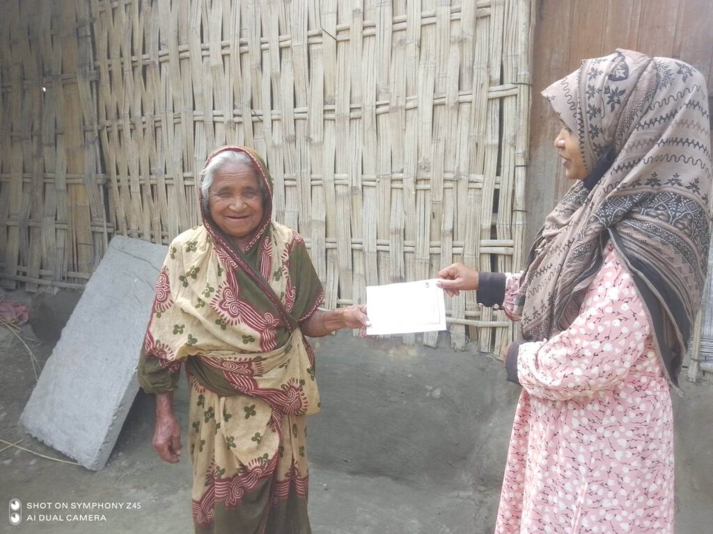Jovial Hamida receives her card for collecting Ramadan 2023 Food Pack from Islamic Relief teams in Bangladesh.