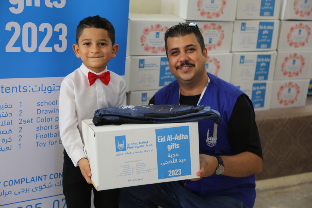 young boy in Iraq receiving Eid gift for Eid Al Adha from Islamic Relief worker