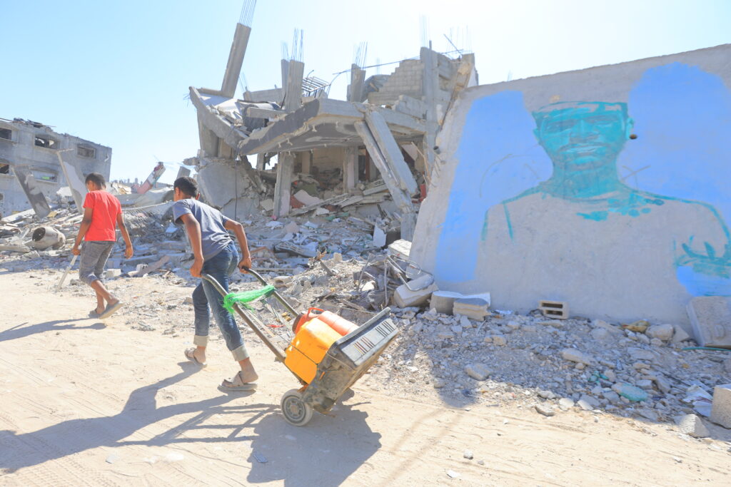 carrying water, humanitarian aid, through the ruins streets of Gaza 