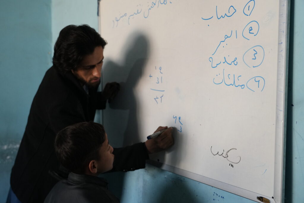 Hijran in school, learning mathematics, watching his teacher write a formula