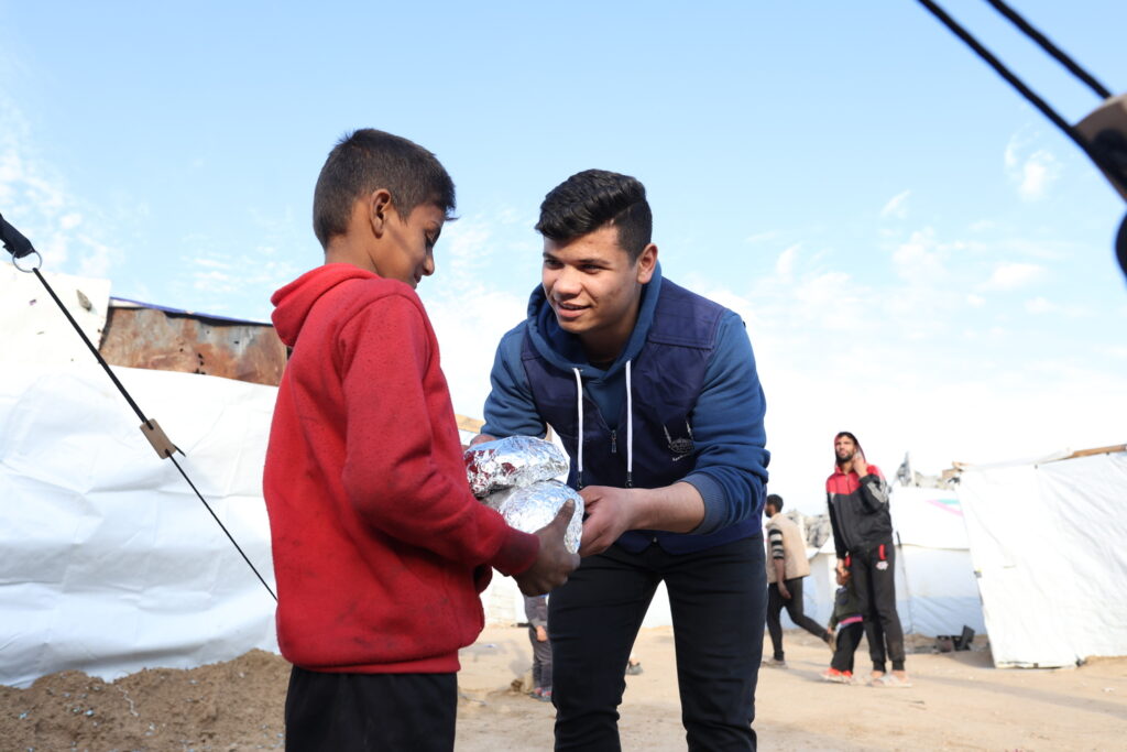 Islamic Relief staff in Gaza handing out aid to the needy (a child) - one of the recipients of zakat