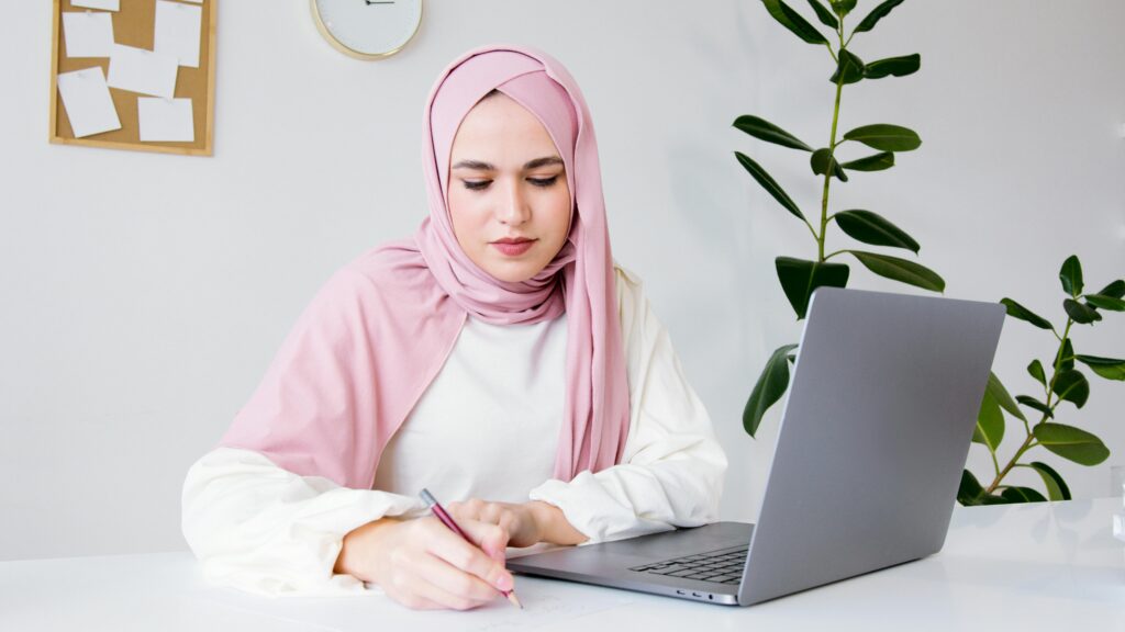 Muslim lady writing with a laptop, deciding what is the best charity to give during Ramadan 