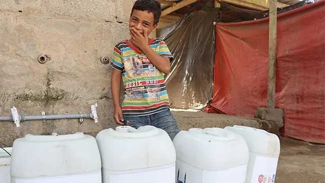 A young boy is thrilled as he receives water storage kits at one of our distributions.